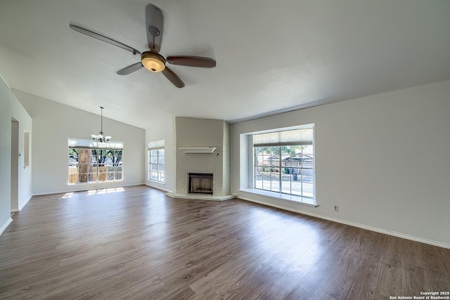 unfurnished living room featuring a fireplace, lofted ceiling, dark wood-type flooring, baseboards, and ceiling fan with notable chandelier