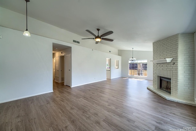 unfurnished living room with lofted ceiling, ceiling fan with notable chandelier, a fireplace, wood finished floors, and visible vents