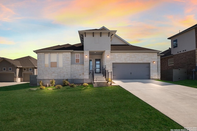 view of front of home with a garage, concrete driveway, a lawn, and stone siding