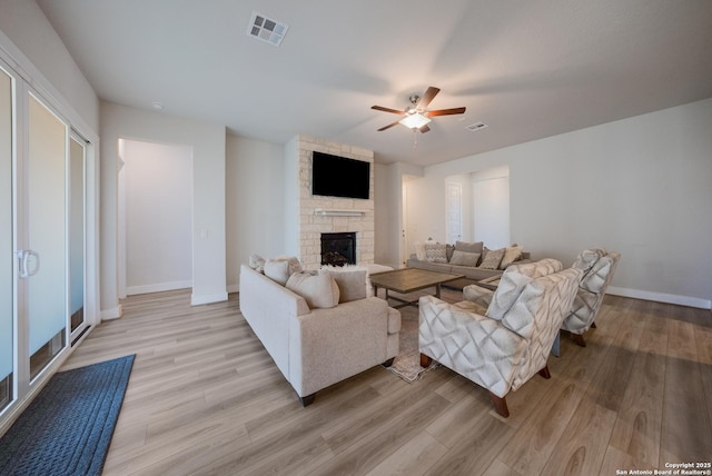 living room featuring a fireplace, visible vents, and light wood-style floors