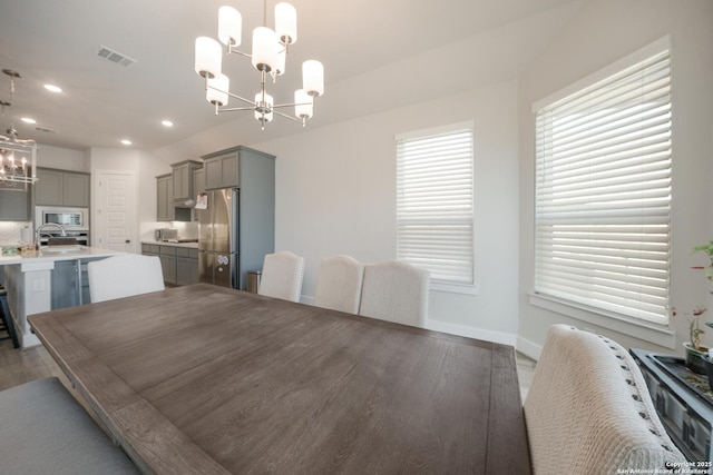 dining area with a chandelier, dark wood finished floors, visible vents, and a healthy amount of sunlight