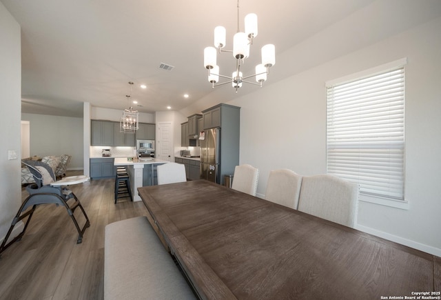 dining area featuring dark wood-type flooring, recessed lighting, visible vents, and a notable chandelier