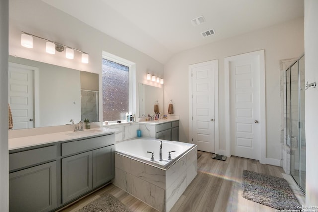 full bath with a stall shower, visible vents, two vanities, and a sink