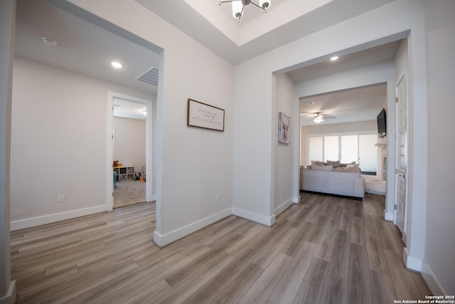 hall featuring baseboards, visible vents, and light wood-style floors