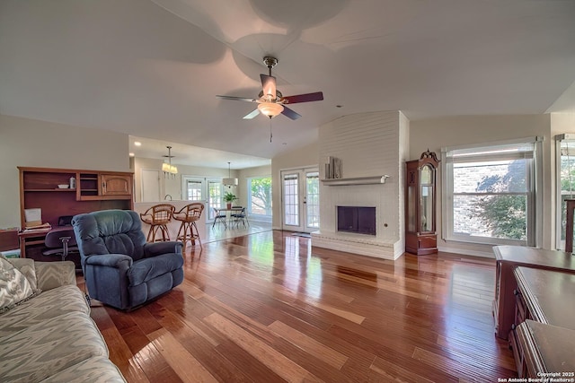 living area featuring lofted ceiling, ceiling fan, wood finished floors, french doors, and a brick fireplace