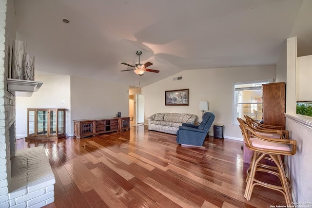 living room with baseboards, visible vents, ceiling fan, wood finished floors, and vaulted ceiling