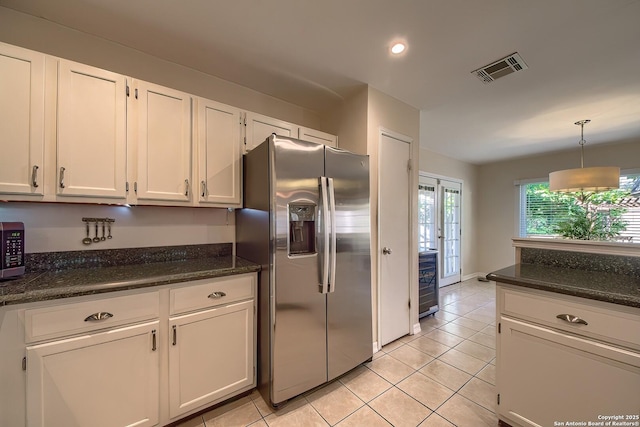 kitchen with light tile patterned flooring, stainless steel appliances, visible vents, white cabinetry, and hanging light fixtures