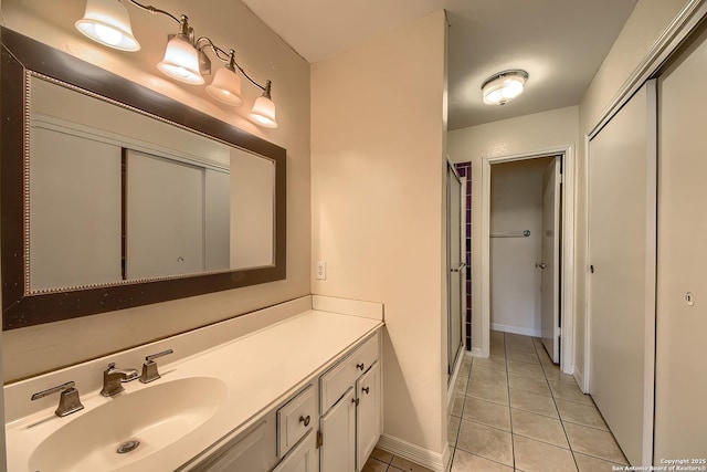 full bath with baseboards, a shower stall, vanity, and tile patterned floors