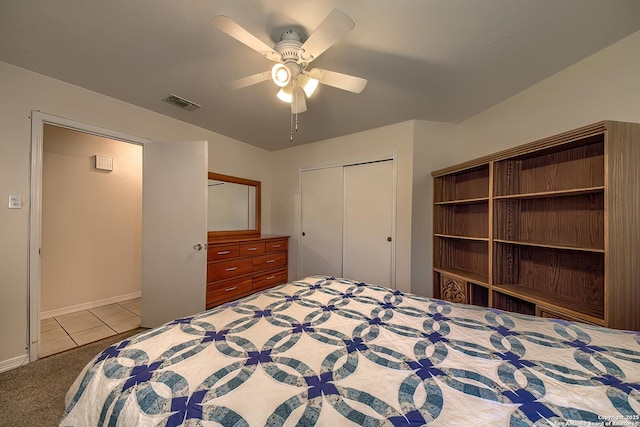 unfurnished bedroom featuring light tile patterned floors, light colored carpet, visible vents, a ceiling fan, and a closet