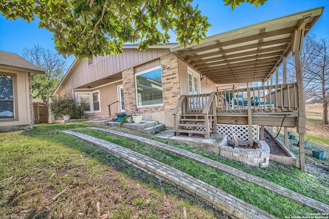 back of house featuring brick siding, a yard, and a deck