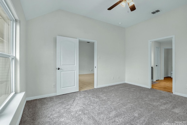 unfurnished bedroom with light carpet, baseboards, visible vents, a ceiling fan, and lofted ceiling