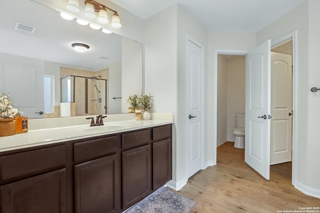 full bathroom with a stall shower, a closet, toilet, and wood finished floors