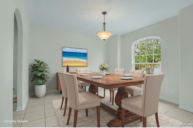 dining room with baseboards, arched walkways, and light tile patterned flooring