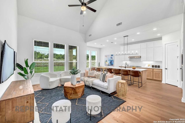 living area featuring recessed lighting, visible vents, light wood-style flooring, a ceiling fan, and high vaulted ceiling