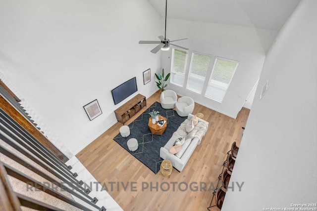 living area featuring high vaulted ceiling, a ceiling fan, and wood finished floors