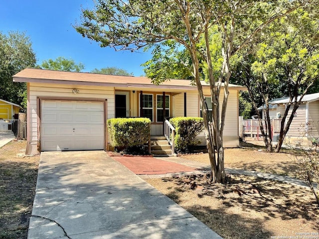 ranch-style home with driveway, covered porch, a garage, and fence