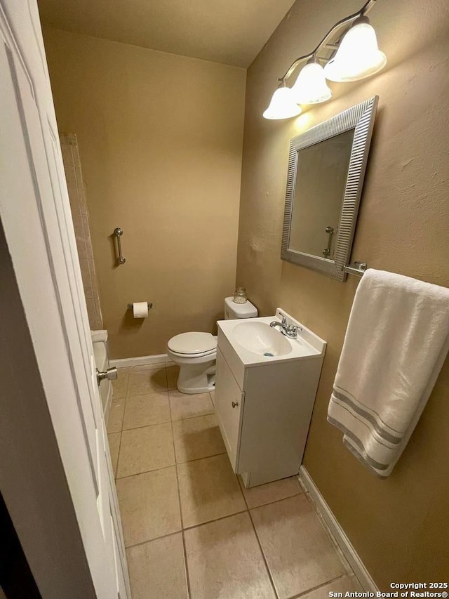 half bathroom with tile patterned flooring, baseboards, vanity, and toilet