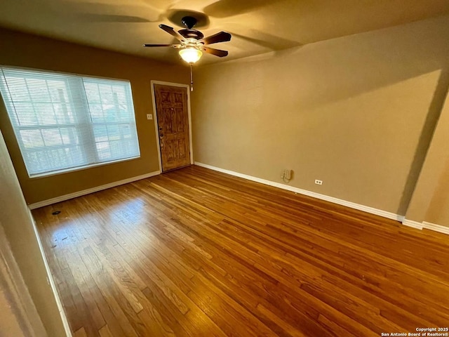 empty room with ceiling fan, hardwood / wood-style flooring, and baseboards