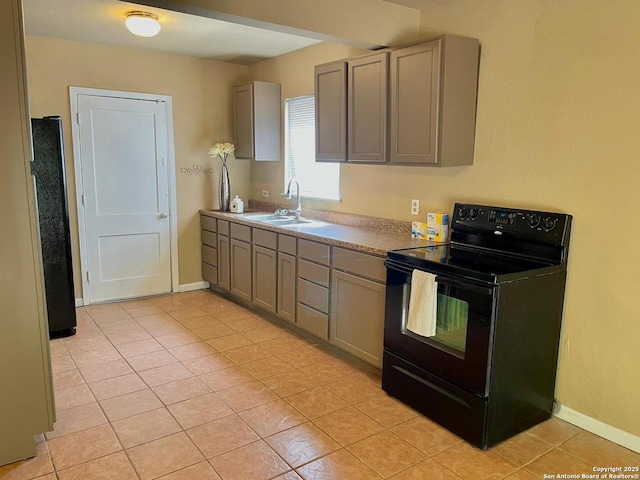 kitchen featuring gray cabinets, light tile patterned flooring, a sink, black appliances, and baseboards