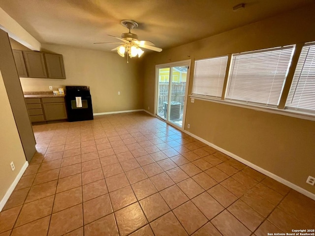 interior space with light tile patterned flooring, a ceiling fan, and baseboards