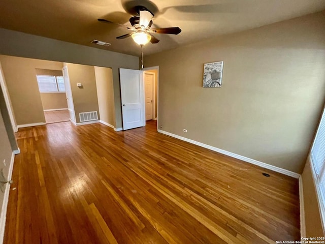 unfurnished bedroom with a ceiling fan, visible vents, baseboards, and wood finished floors