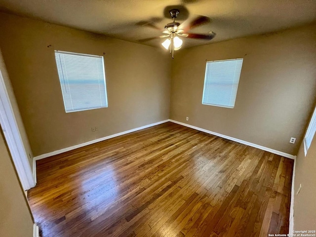 empty room featuring a textured ceiling, wood finished floors, a ceiling fan, and baseboards