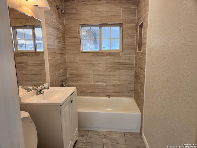 bathroom featuring a textured wall, plenty of natural light, vanity, and tub / shower combination