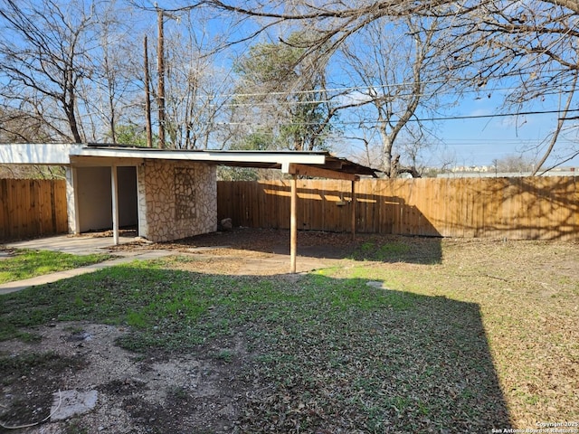 view of yard featuring a fenced backyard and a carport