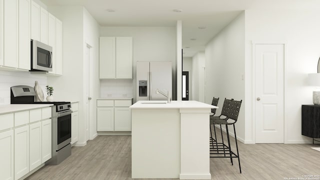 kitchen with stainless steel appliances, light countertops, a center island with sink, and white cabinets