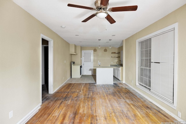 unfurnished living room featuring washer / dryer, baseboards, and wood finished floors