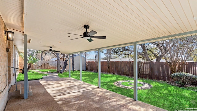 view of patio / terrace with a storage unit, an outdoor structure, a fenced backyard, and a ceiling fan