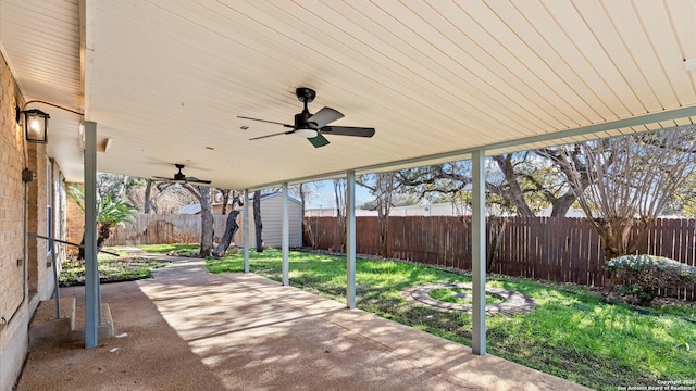 view of patio featuring an outbuilding, ceiling fan, a storage unit, and a fenced backyard