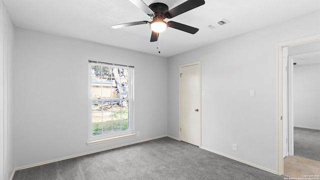 unfurnished room with carpet floors, visible vents, ceiling fan, and baseboards