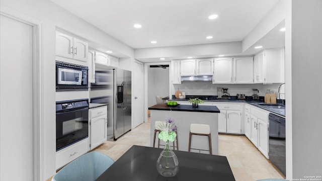 kitchen with under cabinet range hood, white cabinets, a center island, black appliances, and dark countertops