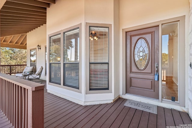 view of exterior entry with covered porch and stucco siding