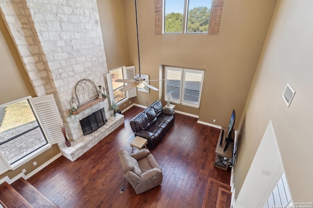 living room with plenty of natural light, wood-type flooring, and a stone fireplace