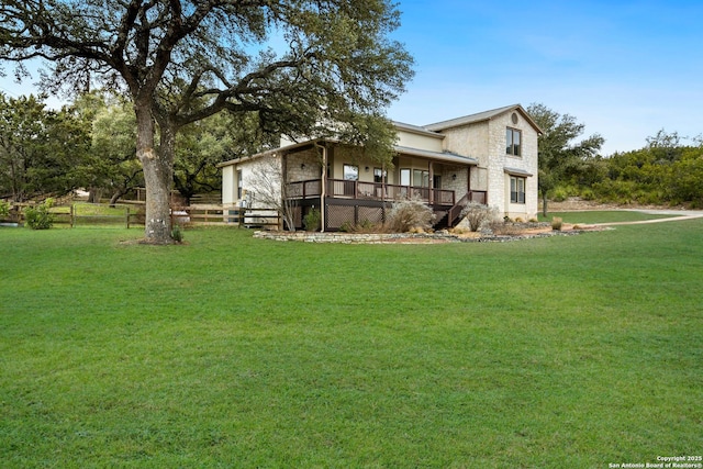 view of front of home featuring stone siding, fence, and a front lawn