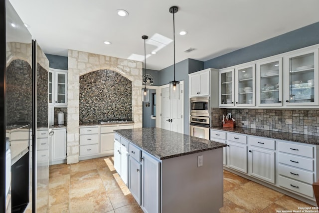 kitchen featuring stainless steel appliances, white cabinets, a kitchen island, and backsplash