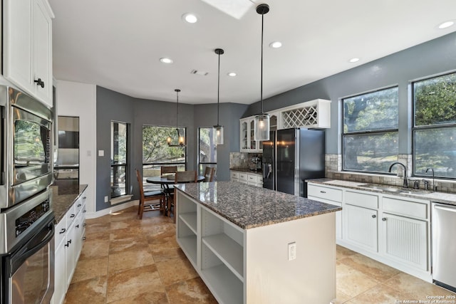 kitchen featuring a kitchen island, a sink, stainless steel appliances, open shelves, and backsplash