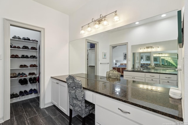 full bathroom featuring a walk in closet, vanity, and wood tiled floor