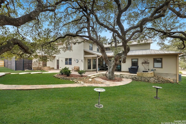 view of front of property featuring metal roof, a standing seam roof, a patio area, and a front yard