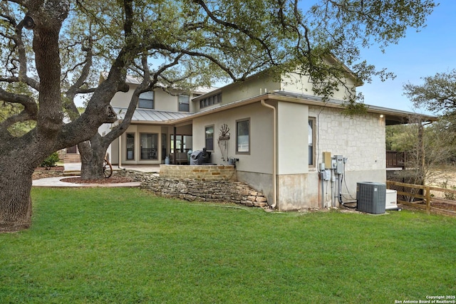 back of property with a yard, a standing seam roof, a patio area, central AC, and metal roof