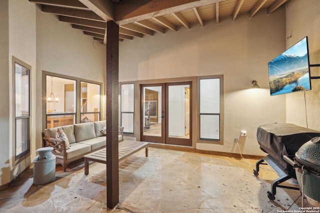 interior space with wood ceiling, french doors, a towering ceiling, and beam ceiling