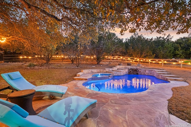 pool at dusk with a patio, fence, and a pool with connected hot tub