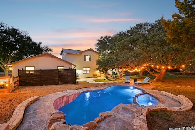 view of swimming pool with a patio area, fence, and a pool with connected hot tub