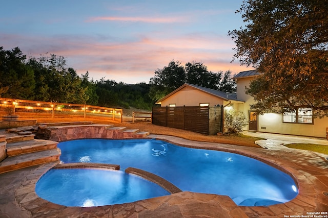 view of pool featuring a patio area, fence, and a pool with connected hot tub