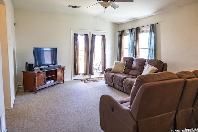 living room with a ceiling fan, light colored carpet, visible vents, and vaulted ceiling