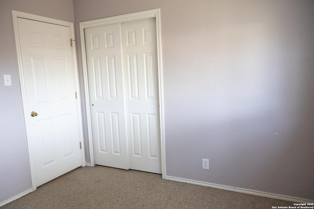 unfurnished bedroom with carpet floors, baseboards, and a closet