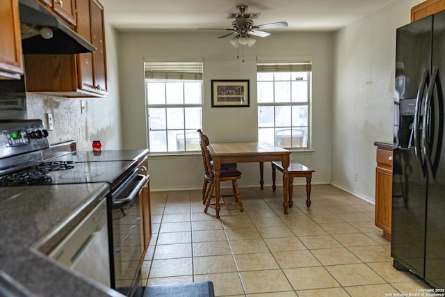 kitchen with dark countertops, black appliances, under cabinet range hood, and brown cabinetry