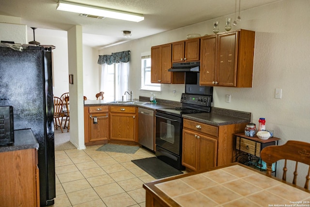 kitchen featuring light tile patterned flooring, under cabinet range hood, a sink, brown cabinets, and black appliances